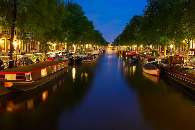 Vue nocturne sur la ville d'amsterdam canal et péniche typique, hollande, pays-bas.