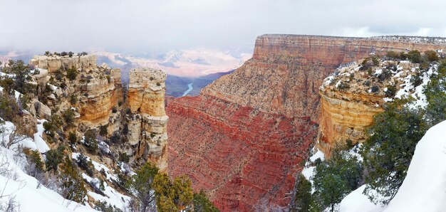 Vue panoramique du Grand Canyon en hiver avec neige et ciel bleu clair.