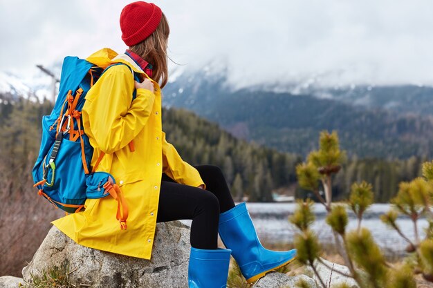 Vue panoramique du touriste féminin actif en imperméable pose sur la rive pittoresque