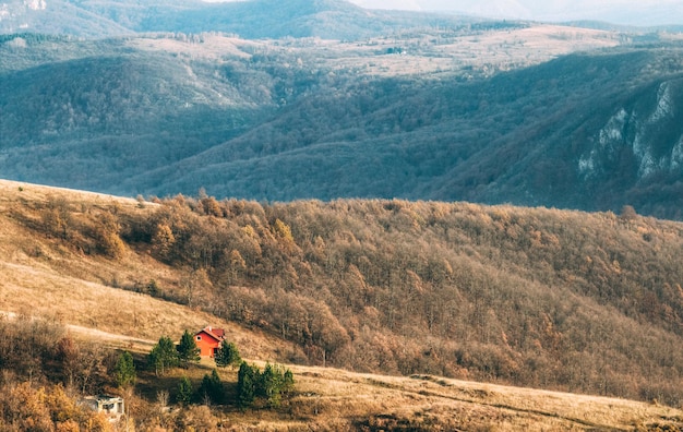 Photo gratuite vue panoramique d'une maison rurale au sommet d'une colline surplombant le magnifique paysage de montagne