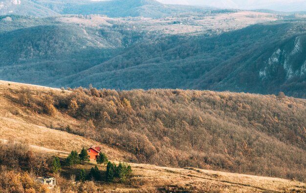 Vue panoramique d'une maison rurale au sommet d'une colline surplombant le magnifique paysage de montagne