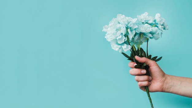 Photo gratuite vue panoramique d'une personne tenant des fleurs artificielles à la main