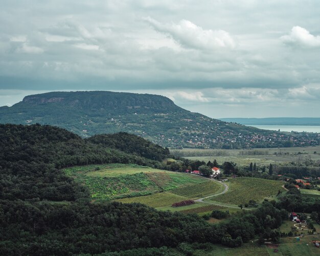 Vue paysage des champs et des collines au bord d'un lac par temps nuageux