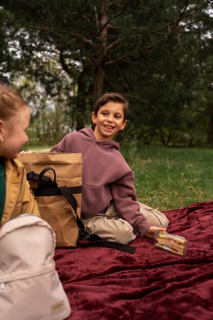 Photo gratuite vue de petits enfants avec des sacs à dos passant du temps dans la nature à l'extérieur