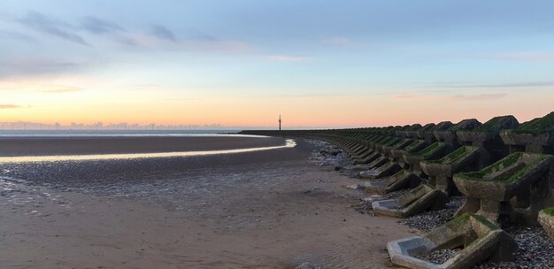 Vue de la plage de Liverpool au coucher du soleil, des rangées de brise-lames, Royaume-Uni