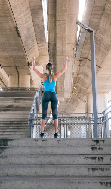 Vue postérieure, de, jeune femme, debout, sur, escalier, levant bras