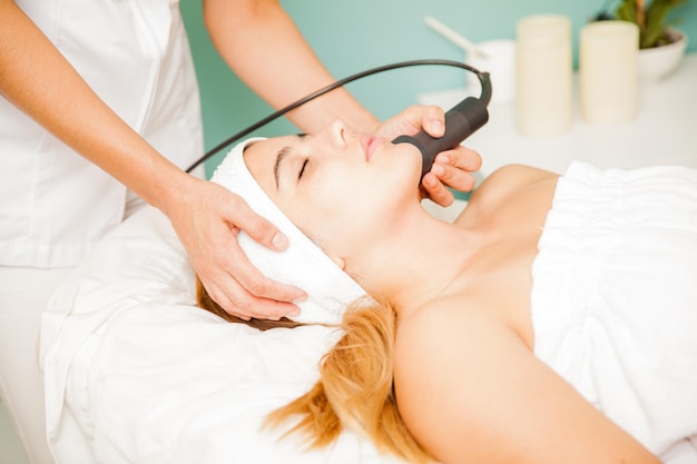 Vue de profil d'une jeune brune lors d'une séance de thérapie faciale dans un spa de santé et de beauté