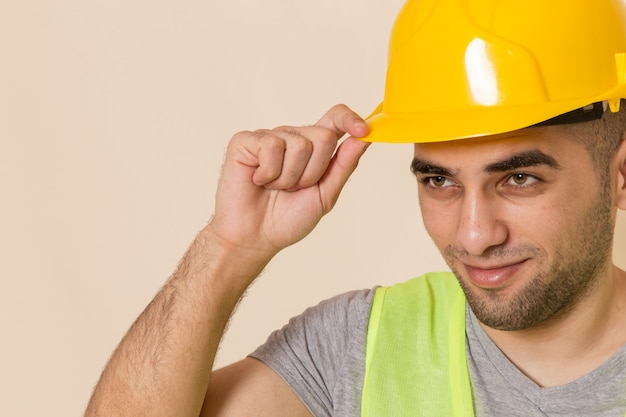 Photo gratuite vue rapprochée avant constructeur masculin en casque jaune posant sur fond clair