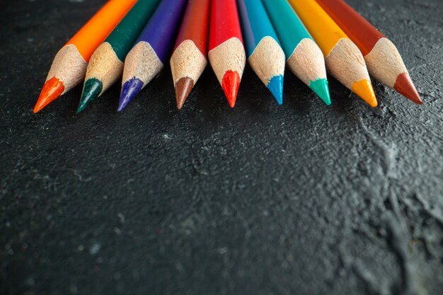 Vue rapprochée avant des crayons colorés bordés d'une école d'art photo couleur dessin sombre