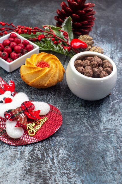 Vue rapprochée avant d'un délicieux accessoire de décoration de biscuits Santa Claus chaussette et cornell dans un bol de branches de sapin sur une surface sombre