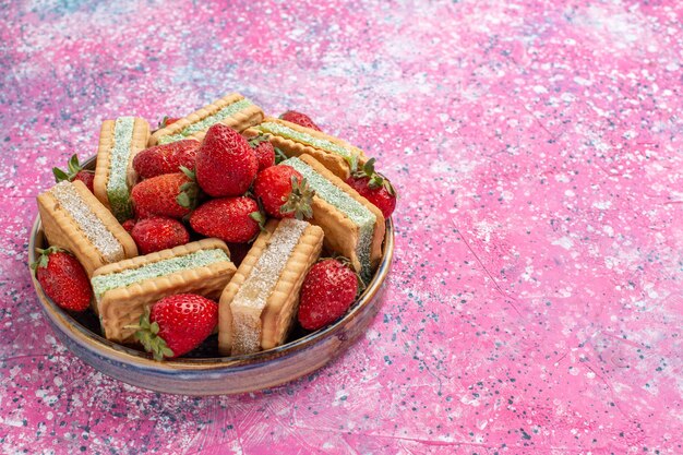 Vue rapprochée avant de délicieux biscuits gaufres avec des fraises rouges fraîches sur mur rose