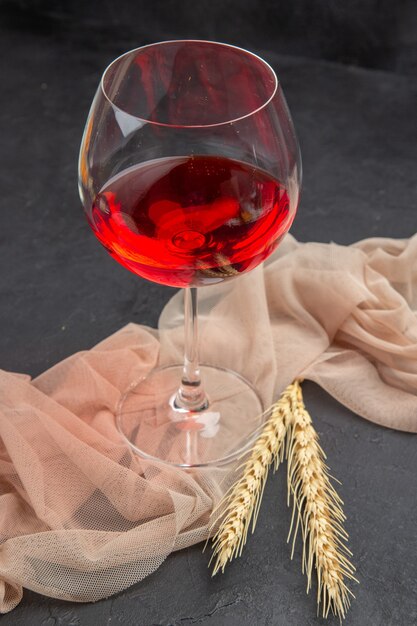 Vue rapprochée avant du vin rouge dans un gobelet en verre sur une serviette sur fond noir