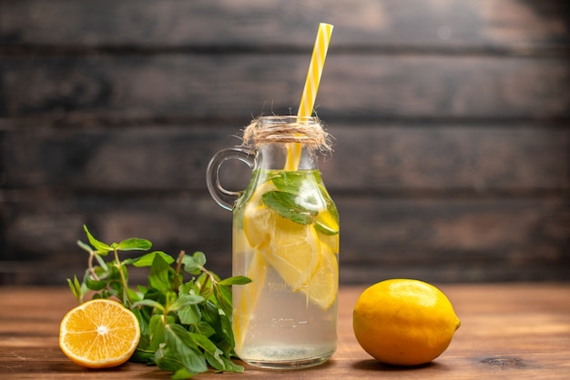 Vue rapprochée avant de l'eau de désintoxication fraîche servie avec de la menthe en tube et de l'orange sur fond marron