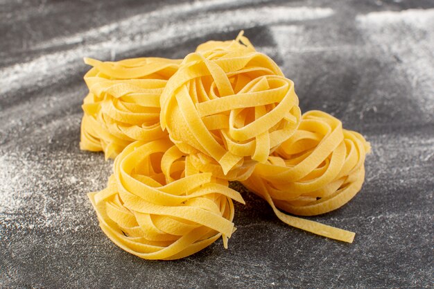 Vue rapprochée avant en forme de pâtes italiennes en forme de fleur crue et jaune sur le bureau gris