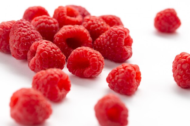 Vue rapprochée avant de framboises rouges fraîches moelleuses et aigres sur toute la surface blanche