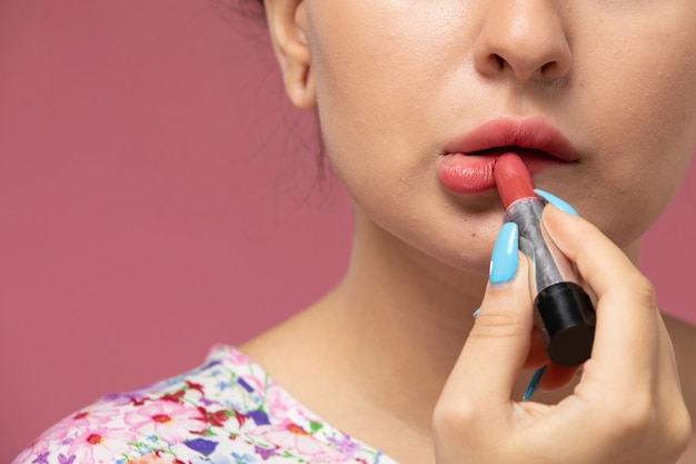 Vue rapprochée avant jeune femme en chemise conçue de fleurs faisant du maquillage sur le fond rose