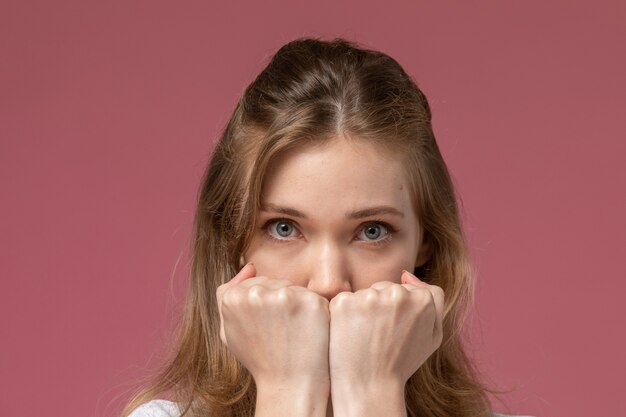Vue rapprochée avant jeune femme séduisante posant avec bouche couverte sur le modèle de bureau rose couleur femme jeune fille