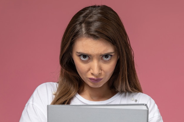 Vue rapprochée avant jeune femme en t-shirt blanc avec une expression mécontente sur rose, modèle de pose de femme photo