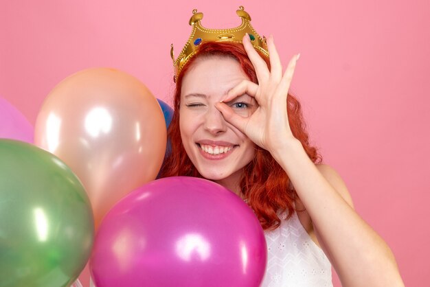 Vue rapprochée avant jeune femme tenant des ballons colorés sur le rose