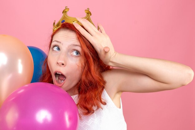 Vue rapprochée avant jeune femme tenant des ballons colorés sur le rose