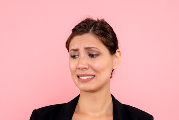 Vue rapprochée avant jeune femme en veste sombre sur fond rose