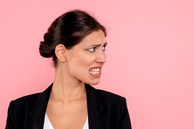 Vue rapprochée avant jeune femme en veste sombre sur fond rose