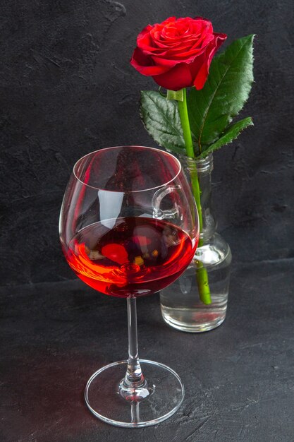 Vue rapprochée avant de la rose rouge dans un vase rempli d'eau et de vin rouge sur fond noir