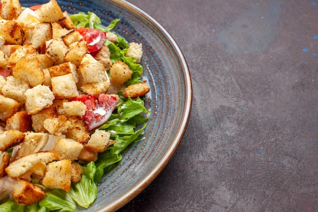 Vue rapprochée avant salade César avec des légumes et des biscottes sur une surface sombre