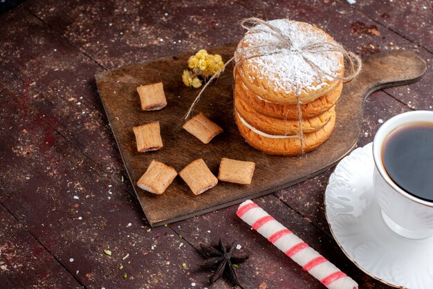 Vue rapprochée avant tasse de café fort et chaud avec des biscuits et des biscuits sandwich sur brun en bois