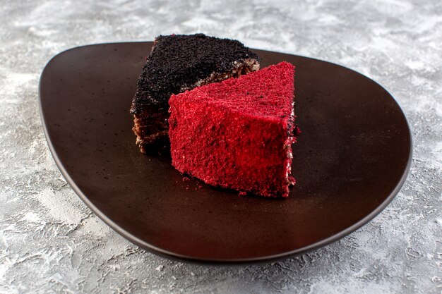 Vue rapprochée avant de tranches de gâteau de couleur chocolat et morceaux de gâteau aux fruits à l'intérieur de la plaque brune