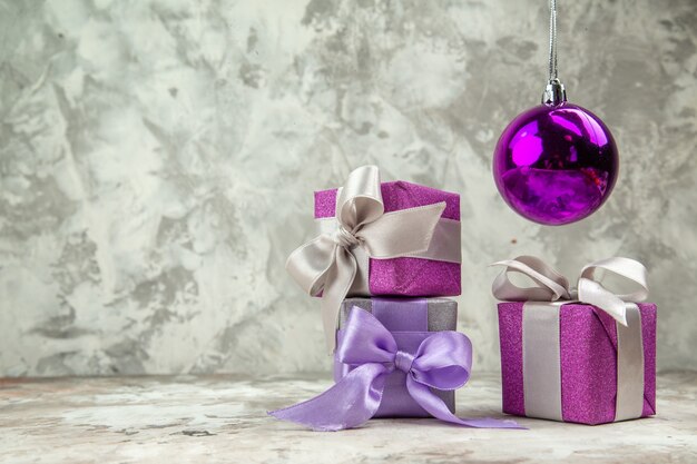 Vue rapprochée avant de trois cadeaux de Noël pour les membres de la famille et d'un accessoire de décoration sur fond de glace