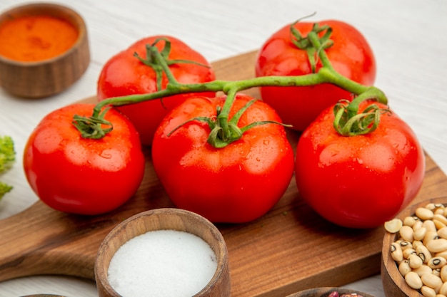 Vue rapprochée en bas de la branche de tomate sur une planche à découper le curcuma salé sur une table grise