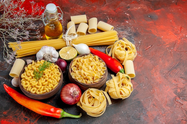 Vue rapprochée de la bouteille d'huile de pâtes non cuites et des aliments pour la préparation du dîner sur la table de couleurs mixtes