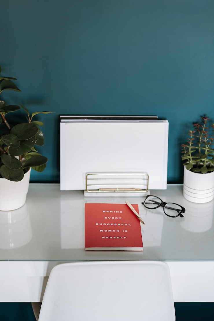 Photo gratuit vue rapprochée d'un bureau blanc avec des livres blancs, cahier rouge, plantes, stylo et verres en elle