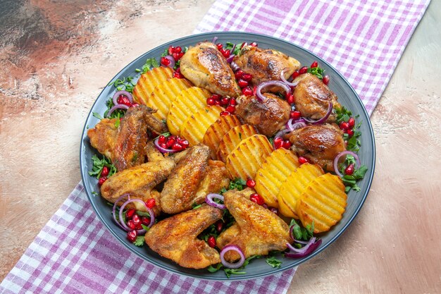 Vue rapprochée de côté assiette de poulet de pommes de terre au poulet oignon herbes sur la nappe