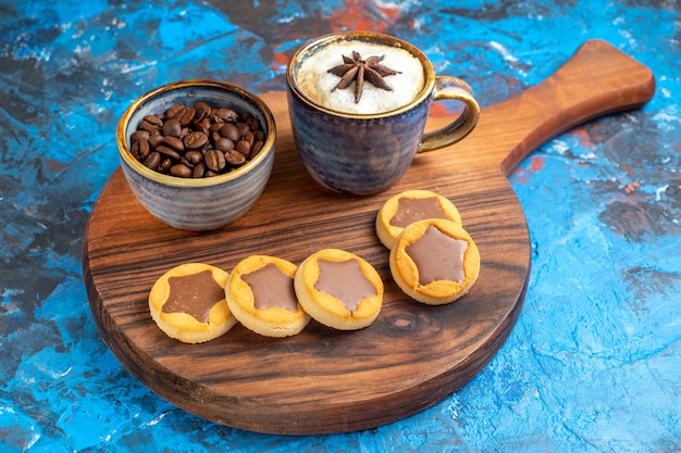 Vue rapprochée de côté bonbons une tasse de biscuits au café et grains de café sur la planche