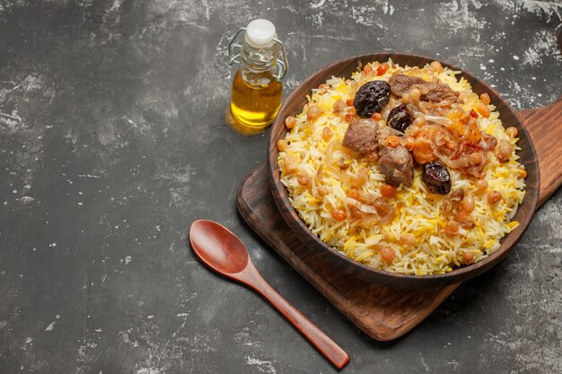 Vue rapprochée de côté épices pilaf sur la planche à découper cuillère bouteille d'huile