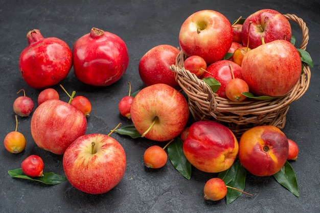 Vue rapprochée de côté fruits le panier en bois de pommes cerises feuilles grenades nectarines