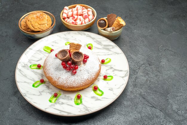 Vue rapprochée de côté un gâteau un gâteau aux groseilles rouges bonbons biscuits gaufres