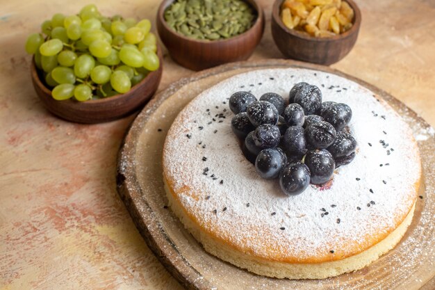 Vue rapprochée de côté un gâteau un gâteau sur le conseil raisins raisins verts graines de citrouille