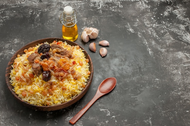 Vue rapprochée de côté pilaf un appétissant bouteille d'ail pilaf d'huile cuillère en bois