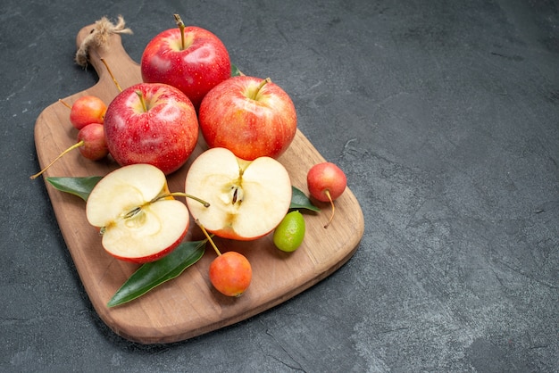 Photo gratuite vue rapprochée de côté les pommes les appétissants agrumes cerises et pommes sur la planche de bois