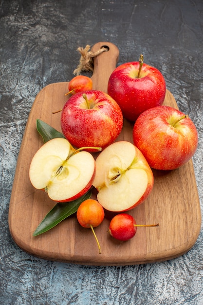 Vue rapprochée de côté les pommes les pommes rouges appétissantes sur la planche à découper