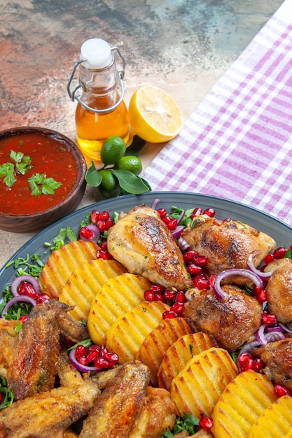 Photo gratuite vue rapprochée de côté poulet les pommes de terre appétissantes ailes de poulet herbes sauce oignon bouteille d'huile