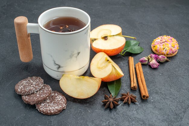 Vue rapprochée de côté une tasse de biscuits au thé une tasse de tisane tranches de pomme bâtons de cannelle