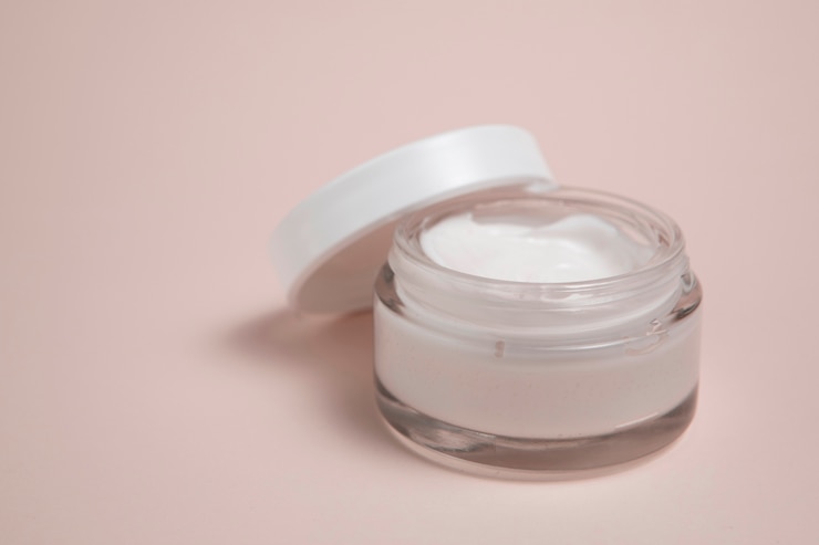 Photo gratuit vue rapprochée de la crème pour le corps sur fond rose