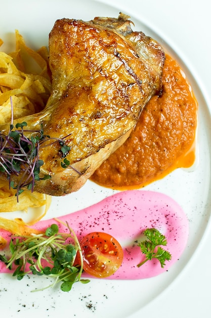 Photo gratuite vue rapprochée de la cuisse de poulet rôti servi avec des croustilles et du caviar d'aubergine sur plaque blanche