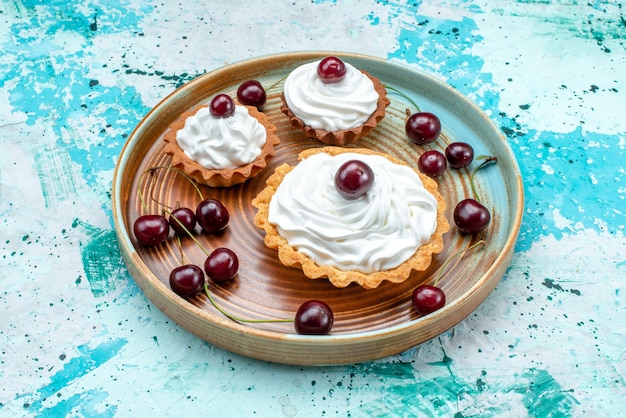 Vue rapprochée de cupcake à la crème et quelques cerises sur bleu,