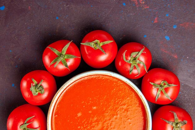 Photo gratuite vue rapprochée de la délicieuse soupe aux tomates entourée de tomates rouges fraîches sur l'espace sombre