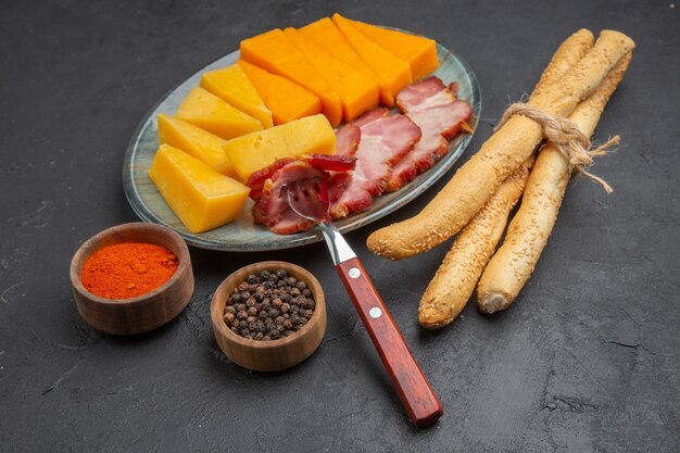 Vue rapprochée d'une délicieuse tranche de saucisse et de fromage sur une assiette bleue poivrons sur fond sombre